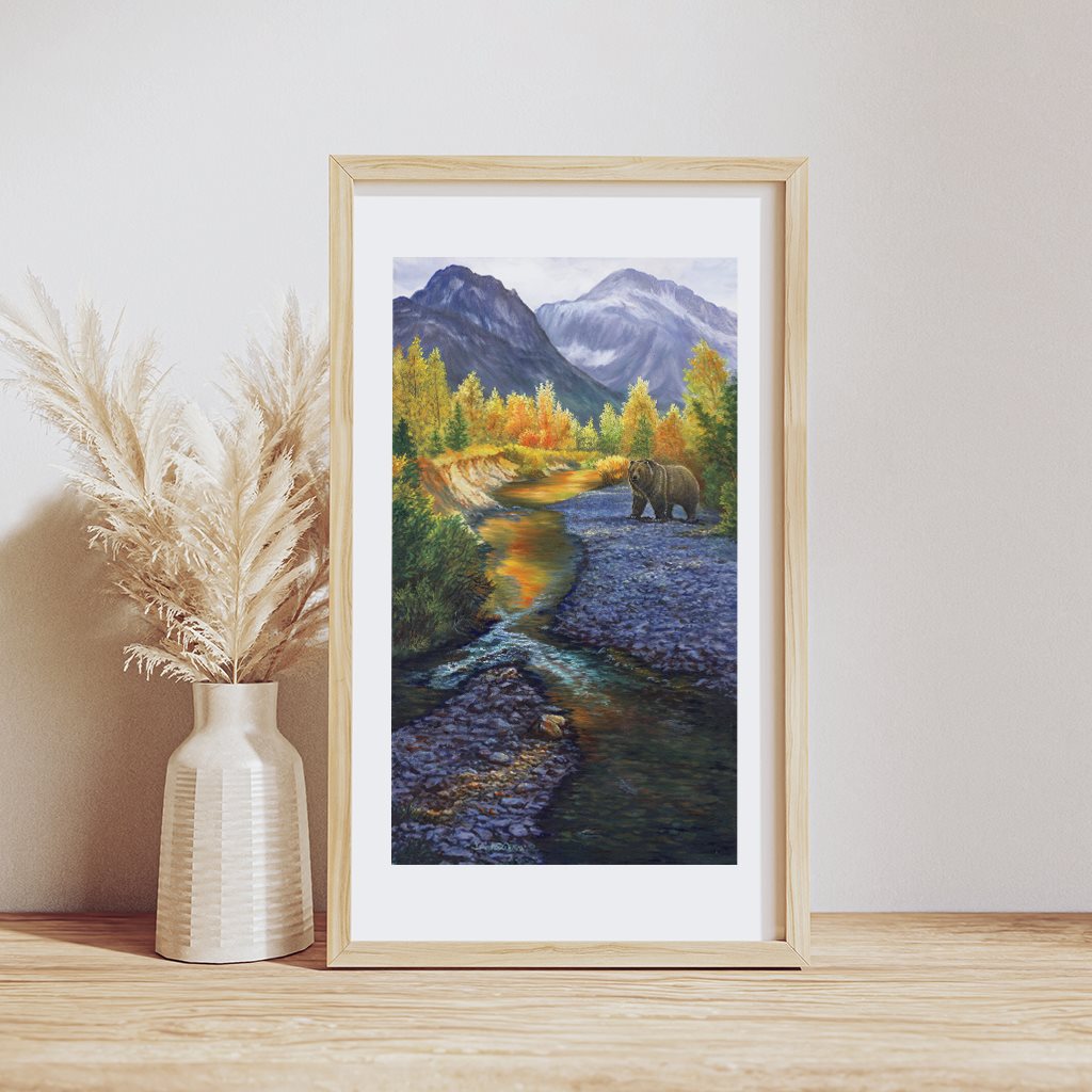 Grizzly Mountain giclée paper print in a natural wood frame, resting on a wooden table. By artist Jeanne Warren