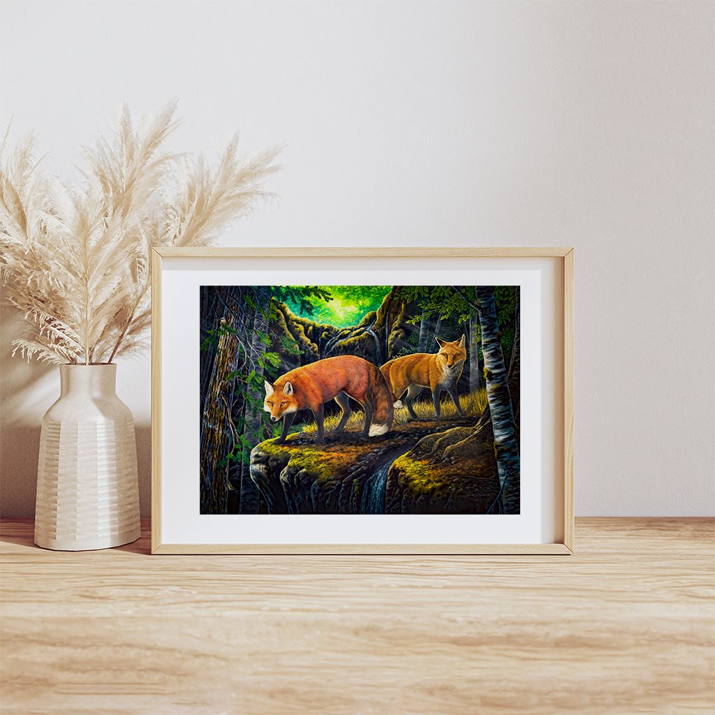 Hideaway - Wild red foxes in a fantasy forest painting giclée paper print in natural wood frame, resting on a wooden table. By artist Jeanne Warren
